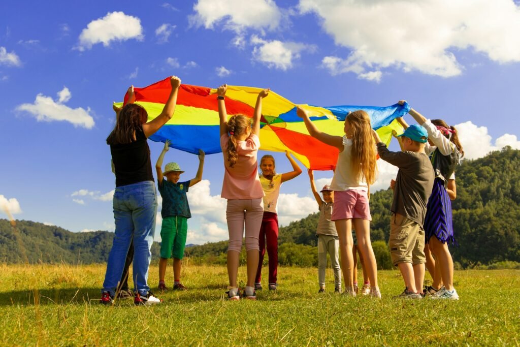 group of children playing outdoors in a grassy field, holding up a large, colorful parachute.
best teacher training institute Borivali, Mumbai.