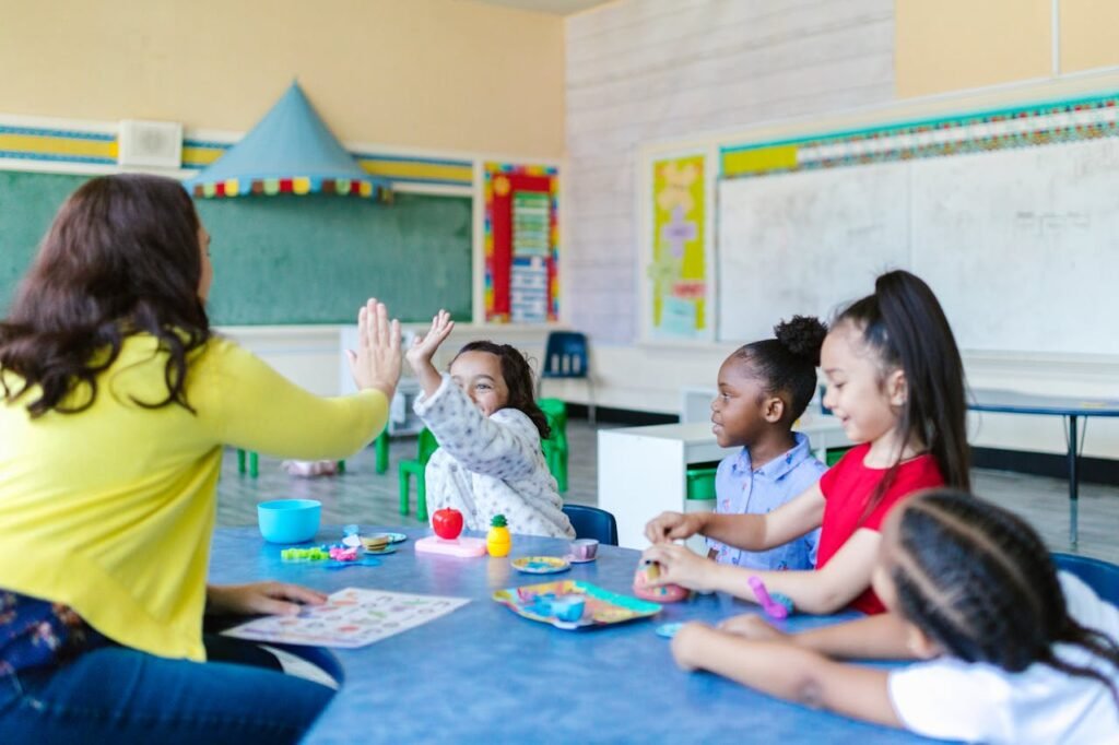 A teacher high-fives a happy child in a colorful classroom. Children play with toys and learn together.