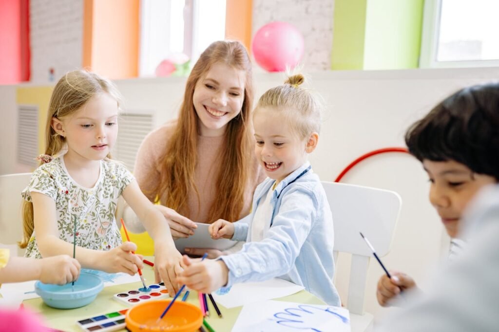 A teacher and a group of children joyfully painting together, surrounded by colorful art supplies and bright smiles.