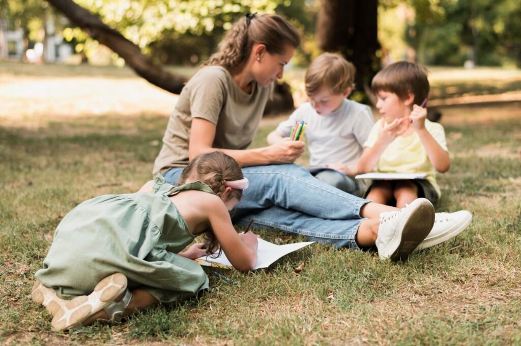 teacher-kids-sitting-grass-full-shot